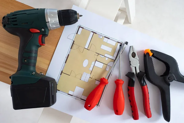 Builder tools on a white background. Architectural drawings next to construction tool. Screwdriver and screwdrivers lie side by side. Concept - things of repairman. Home renovation tools.