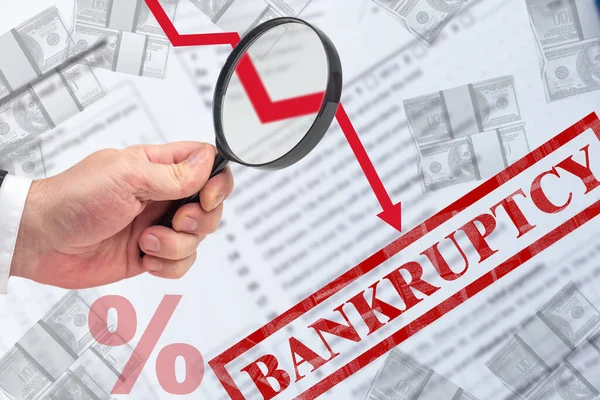 Bankruptcy due to falling incomes. Hand with a magnifier next to bankruptcy logo. Down arrow symbolizes a decrease in revenue. Decrease in profit of companies. Bankrupt. Business devastation.