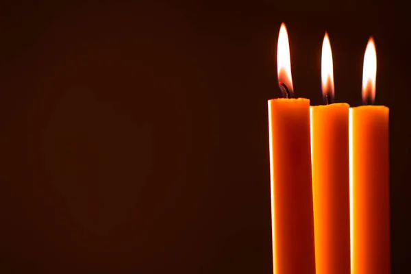 Three candles are lit on a black background. Three candles with flames. Three candles are lit for the spirituality ceremony on a black background. Space for text.