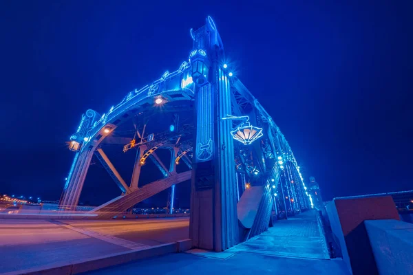 A garlanded bridge against a dark sky. The bridge is decorated for Christmas. Saint Petersburg Bridges. Bolsheokhtinsky bridge in the evening. View of the evening city. New year in Russia.