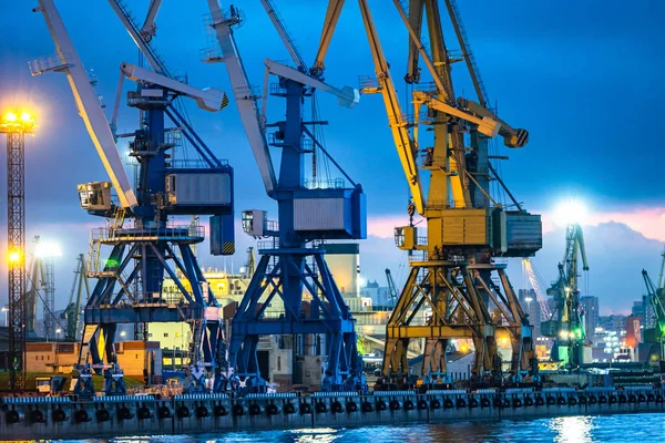 Sea ports view from sea. Several loading cranes at seaport. Installations for loading in seaport. Tower cranes at the cargo port. Marine loading terminal on background of the evening sky.