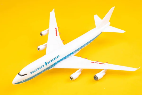 Airplane on a yellow background. Concept - air traffic. Concept - air traffic. Passenger airliner. Miniature civilian aircraft. Civil Aviation. Concept - piloting aircraft. Toy plane collectibles