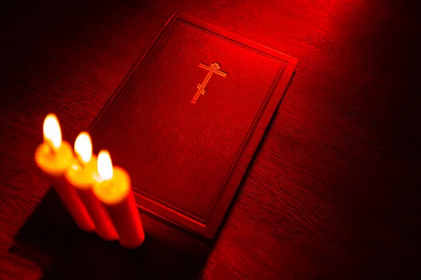 Church candles next to bible. Bible on a wooden table top view. Ortodox cross as a symbol of Christianity. Religious book made of leather. Concept - studying religion. Bible and candles close up