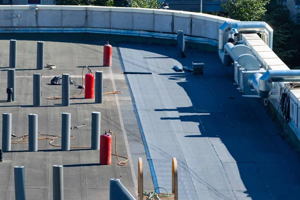 Building roof with rolls for waterproofing. Roof covering with waterproofing materials. Roof covering with protective materials. View top. Preparation for applying bitumen insulating layer.