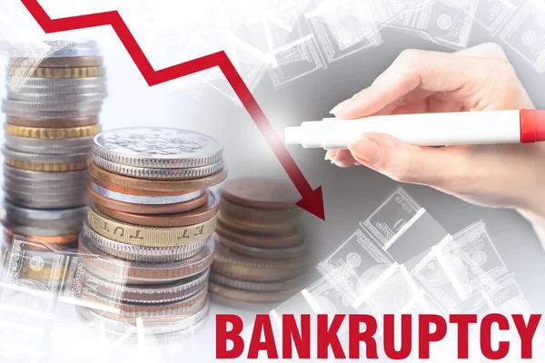 Bankruptcy. A critical drop in revenue. Red arrow down and the word Bankruptcy on the background of money. The person draws a down arrow on the background of coins and bills.