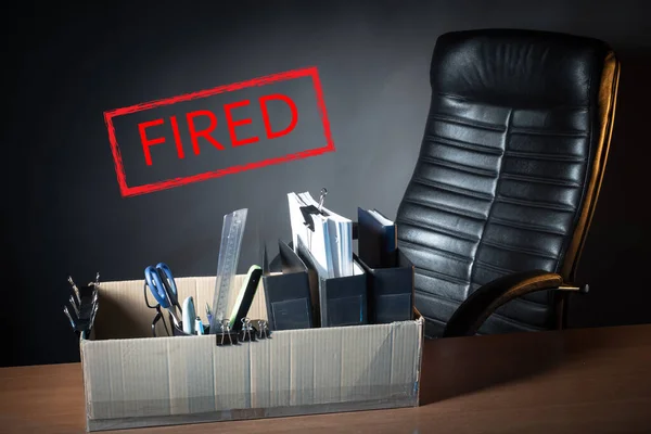 Inscription fired next to work chair. The concept is a fired manager or office worker. Reduction of staff in corporations. fired box on the desktop. Dismissal of a manager due to default