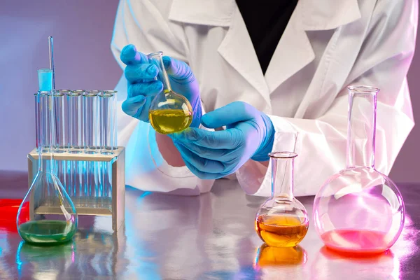 Laboratory testing. A test tube in the hands of a physician as a symbol of laboratory testing of drugs. Pharmacologist is engaged in laboratory testing. Doctor\'s hands with a small flask.