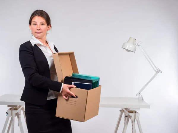 Dismissal. Retirement. Job change. A woman holds a cardboard box with office supplies. Career. Labour activity.