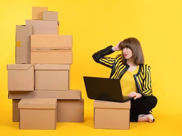 Business parcels. The manager prepares the goods. A woman sends orders from an online store. A woman works behind a laptop on the background of boxes with parcels. Business management.