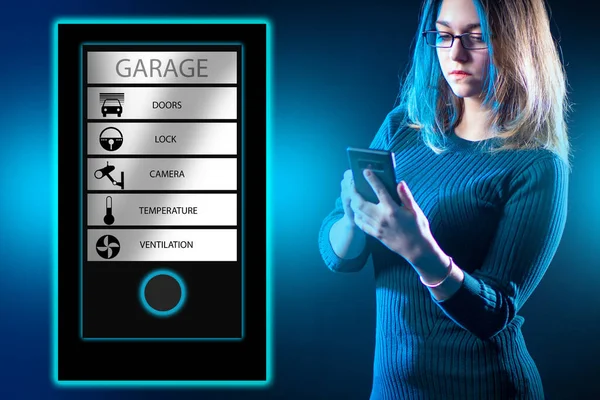 Woman runs garage via a smartphone. Garage IOT system interface is on her phone. System interface IOT automation. Girl with a phone on a dark background. Remote control of ventilation and temperature