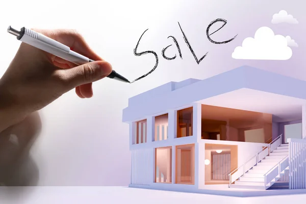 Sale inscription next to house model. Model of a modern house with panoramic windows. Concept - sale of business real estate. Hand with a pen writes word sale. Two-storey house for sale.