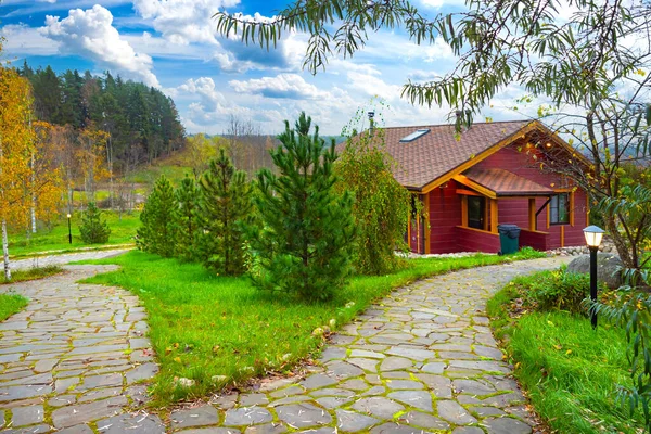 Landscape design house. Wooden house in picturesque place. landscape design of cottage territory. Country cottage on background of autumn forest. Landscape of house is decorated with coniferous trees