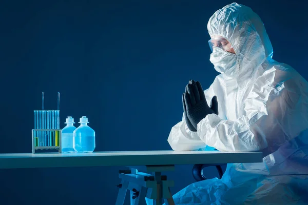 Man in face shield and PPE crossed his arms. Employee of viral lab prays before work. He creates a vaccine against virus. Virologist praying God for a vaccine. Doctor praying during a pandemic
