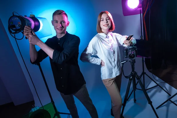 A guy and a girl hold a photo session. Photography in the Studio. Professional photography. A young couple next to lighting fixtures and photographic equipment.