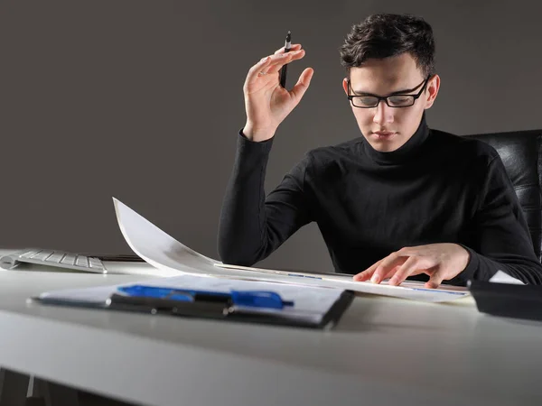 Employee of a consulting company. Young guy at desk. He is considering some documents. Consulting company service concept. Guy works in the consulting business. Business consultant career.