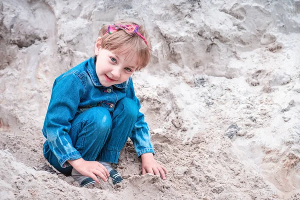 幸せな女の子でデニムスーツ遊びで砂の上の川の銀行 — ストック写真