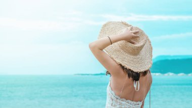 Deniz kenarında şapkasını tutan kız. Seyahat ve tatil kavramı