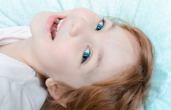 Cheerful child with smile on his face lies on pillow before bed