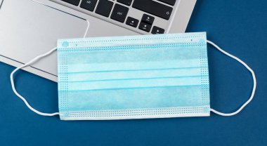 Laptopta tıbbi maske. İnternetteki uzaktan çalışma ve iş kavramı