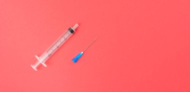 Kırmızı arka planda iğne olan şırınga. Coronavirus aşısı ve enjeksiyon konsepti. Grip aşısı. Şeker hastaları için şırınga