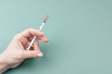 Yeşil arka planda kadın elinde şırınga. Coronavirus aşısı ve enjeksiyon konsepti. Grip aşısı. Şeker hastaları için şırınga