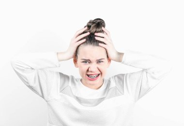 Diş tellerini gösteren elleriyle başını tutan bir kız. Diş hekimliği ve diş teli takma kavramı