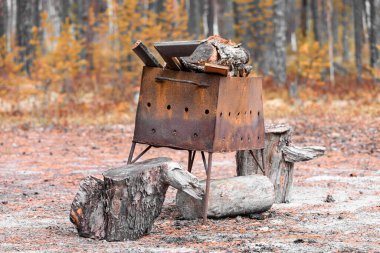 Kebap ve ormanda piknik için yakacak odunu olan paslı mangal.