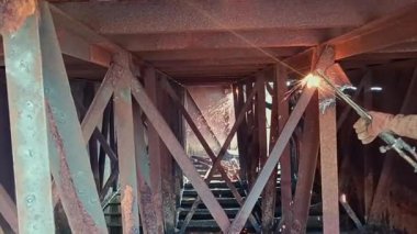 Paslı köprü yapısında metal kirişleri kaynak yapan işçiler
