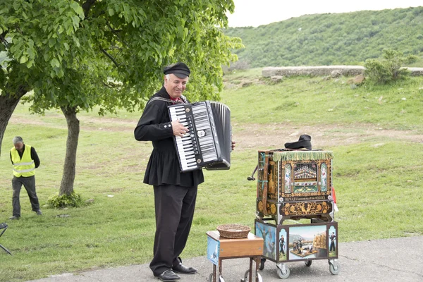 Musicista di strada suona la fisarmonica vicino all'antica chiesa Djvari a Mtsketa, Georgia . — Foto Stock