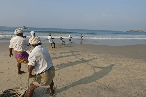 I pescatori indiani tirano le sciabiche fuori dal mare, sulla spiaggia di Kovalam, Kerala, India . — Foto Stock