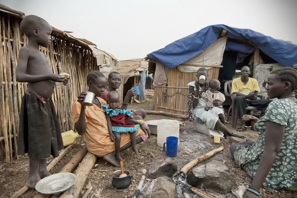 İnsanlar onların kulübelerde önünde zorla göç ettirilmiş kişiler kampı, Juba, Güney Sudan kahvaltınızı.
