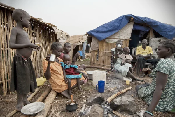 人们在他们的小屋在流离失所者营地，朱巴、 南苏丹前吃早饭. 免版税图库图片