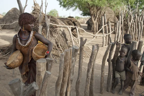 Hamar woman passes by Karo kids, Colcho, Omo Valley, Ethiopia. — Stock Photo, Image