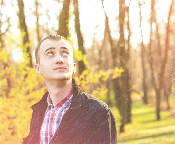 Young attractive man a black jacket in autumn park — Stock Photo, Image