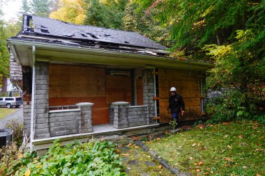 Cornwall, CT, ABD Sigorta müfettişi yangından zarar görmüş ahşap bir evin dış yüzeyini inceliyor..