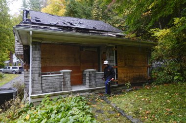 Cornwall, CT, ABD Sigorta müfettişi yangından zarar görmüş ahşap bir evin dış yüzeyini inceliyor..