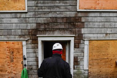 Cornwall, CT, ABD Sigorta müfettişi yangından zarar görmüş ahşap bir evin dış yüzeyini inceliyor..