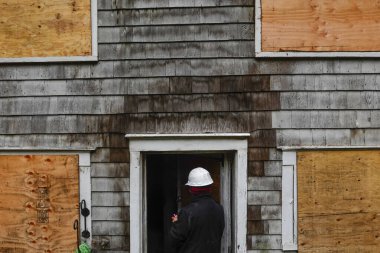 Cornwall, CT, ABD Sigorta müfettişi yangından zarar görmüş ahşap bir evin dış yüzeyini inceliyor..