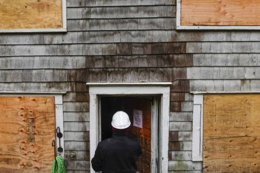 Cornwall, CT, ABD Sigorta müfettişi yangından zarar görmüş ahşap bir evin dış yüzeyini inceliyor..