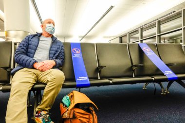 Boston Massachusetts, ABD. Loga Havaalanı 'nın kalkış terminalinde bir adam oturuyor..