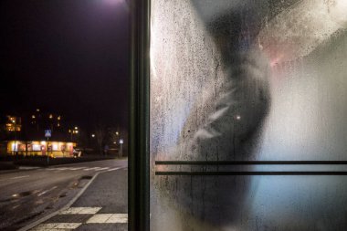 Stockholm, İsveç. Lidingo 'nun varoşlarında yağmurda bir adam otobüs bekliyor..