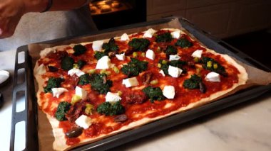Bir insan evde ev yapımı pizza yapar.