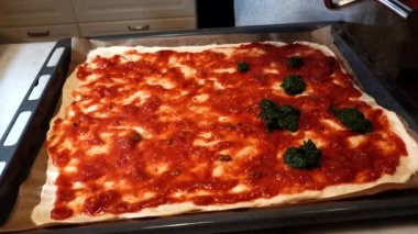 Bir insan evde ev yapımı pizza yapar.
