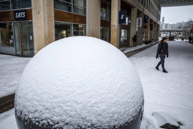 Stockholm, İsveç 'te Marievik' te bir adam karda karla kaplı dev bir dünyanın yanından geçiyor..