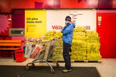Stockholm, İsveç. Maskeli bir kadın Willy 'nin marketinin girişinde duruyor..