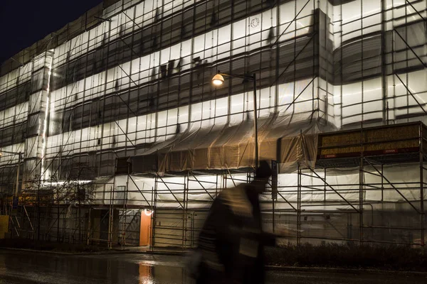 瑞典斯德哥尔摩 Aspudden一个建筑工程的夜间照明和脚手架以及行人 — 图库照片
