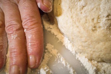 Pizza yapmak için hamur yoğuran bir kadın.