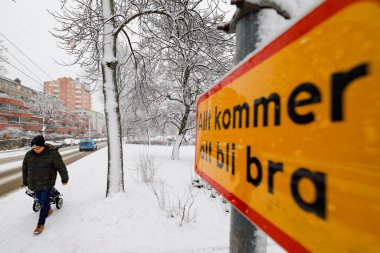 Stockholm, İsveç. Grondal 'da kar altında bir kilisenin önünde sokak tabelası ve yaya. 