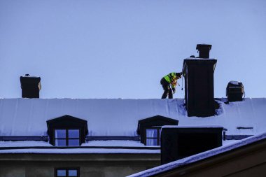 Stockholm, İsveç Bir adam kar küremek için Sodermalm 'in çatılarında devriye geziyor.
