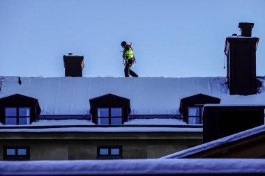Stockholm, İsveç Bir adam kar küremek için Sodermalm 'in çatılarında devriye geziyor.